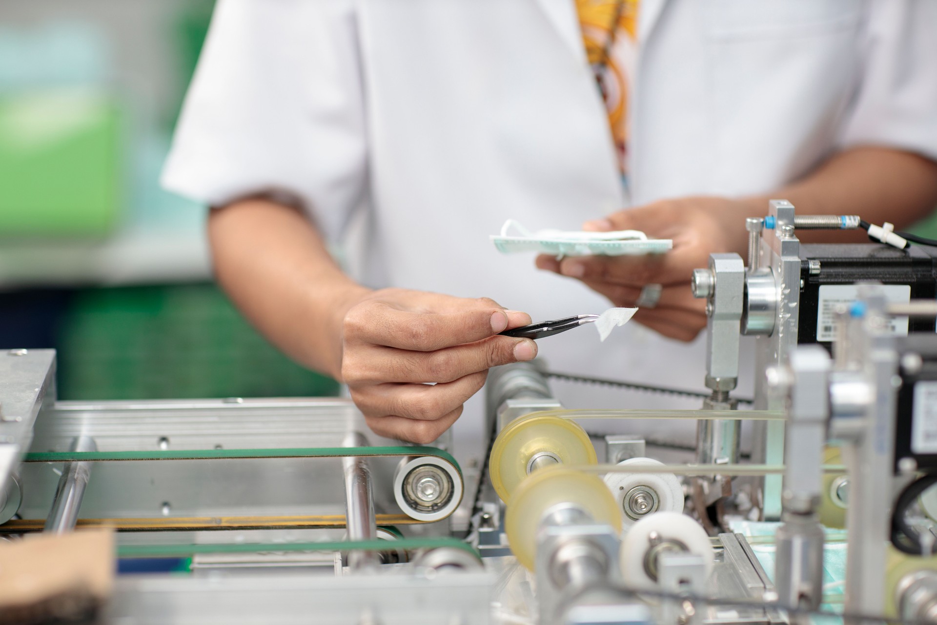 Asian worker hands inspecting quality of mask and medical face mask production line, Industry and factory concept.