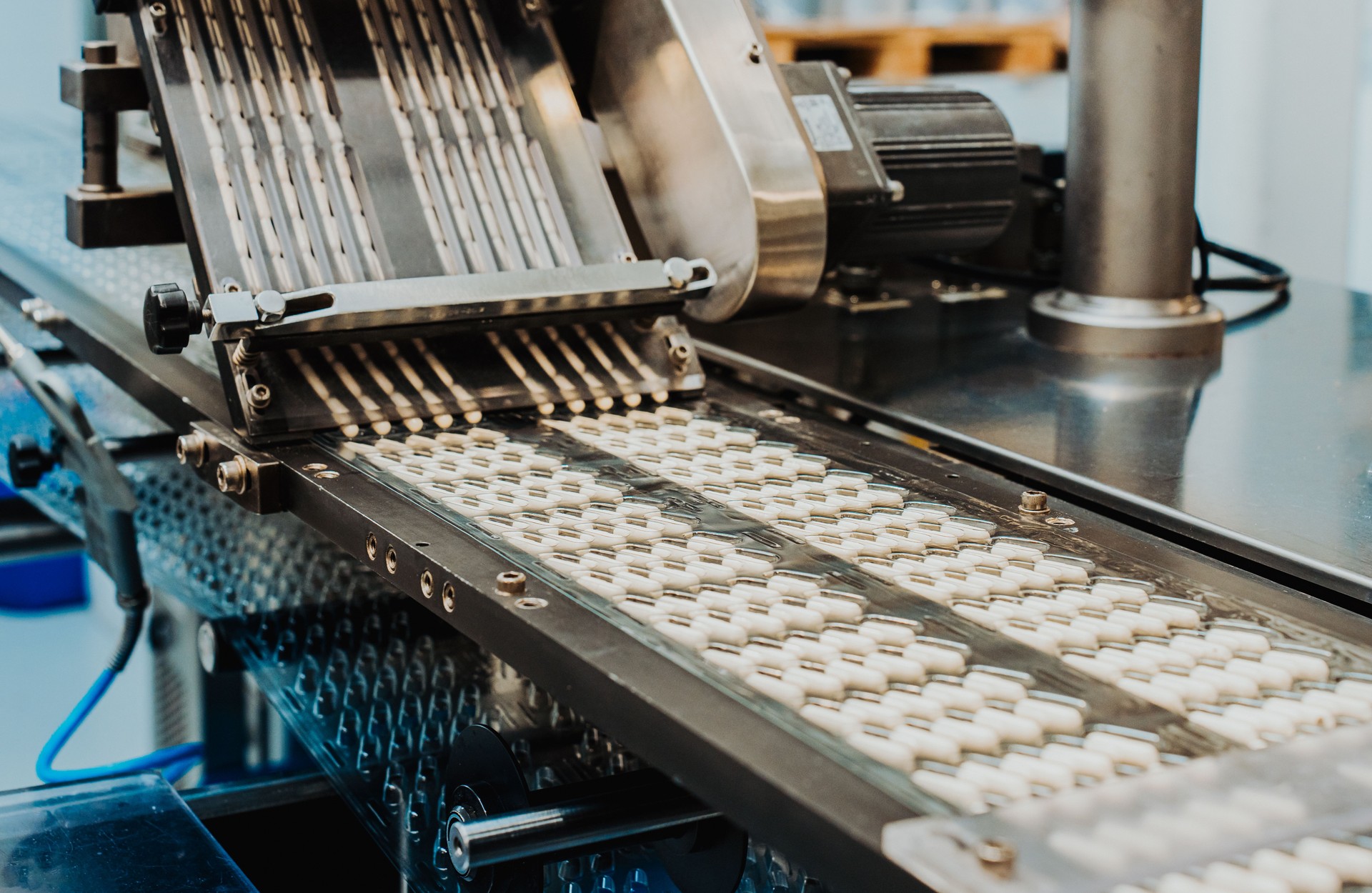 A production line of white pills at the factory. White capsules moving along the production line. Medical factory, machinery for pharmaceutical production. Horizontal frame